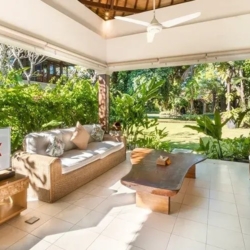 Asraya villa inviting covered terrace with outdoor seating television and views of tropical garden lawn sanur 870x500