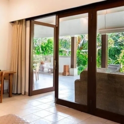 Asraya villa serene villa suite interior with a small wooden desk dark wood door frames and expansive views of the outdoor patio sanur 870x500